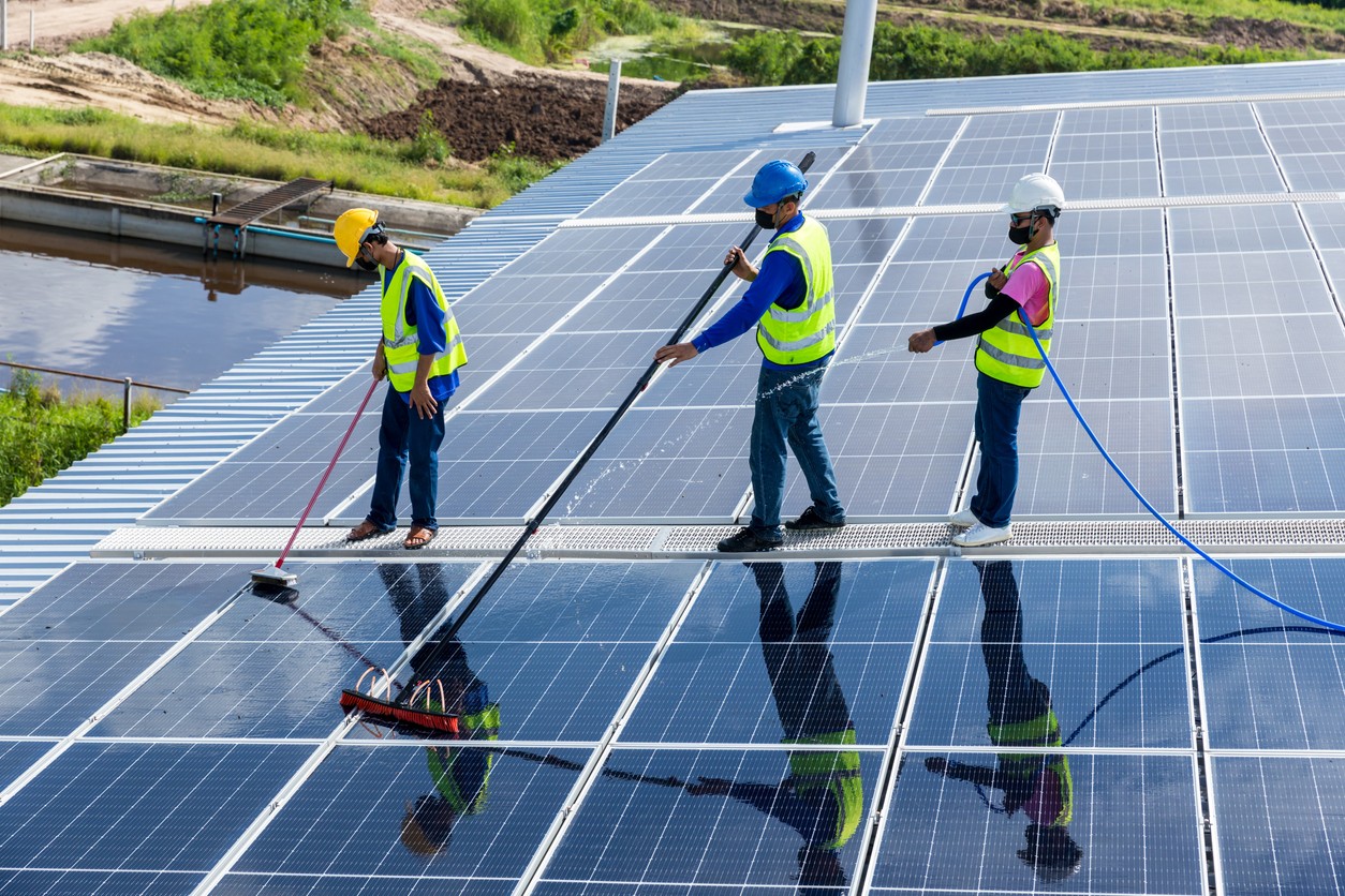 three workers cleaning solar panels